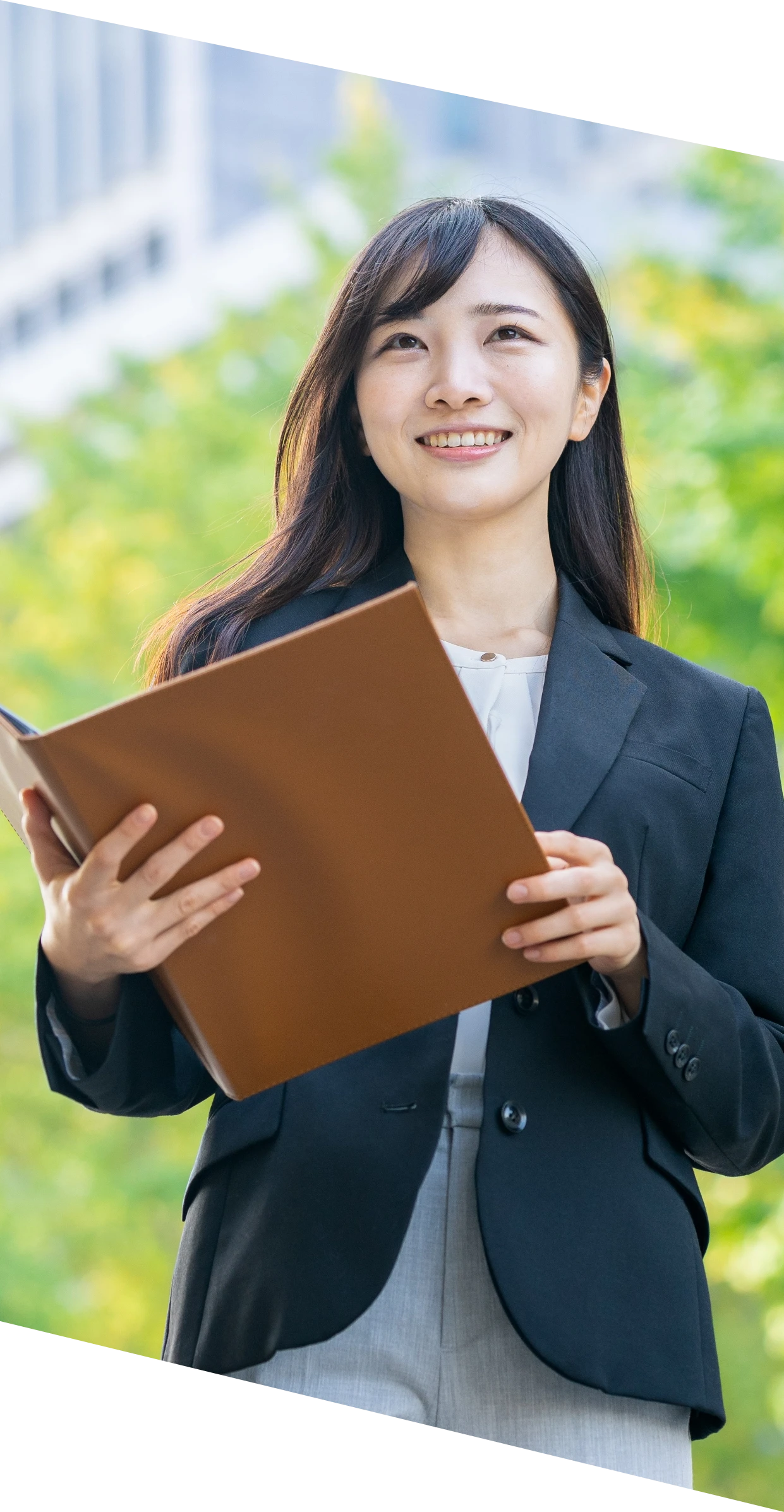 書類ファイルを持って立つスーツ姿の女性