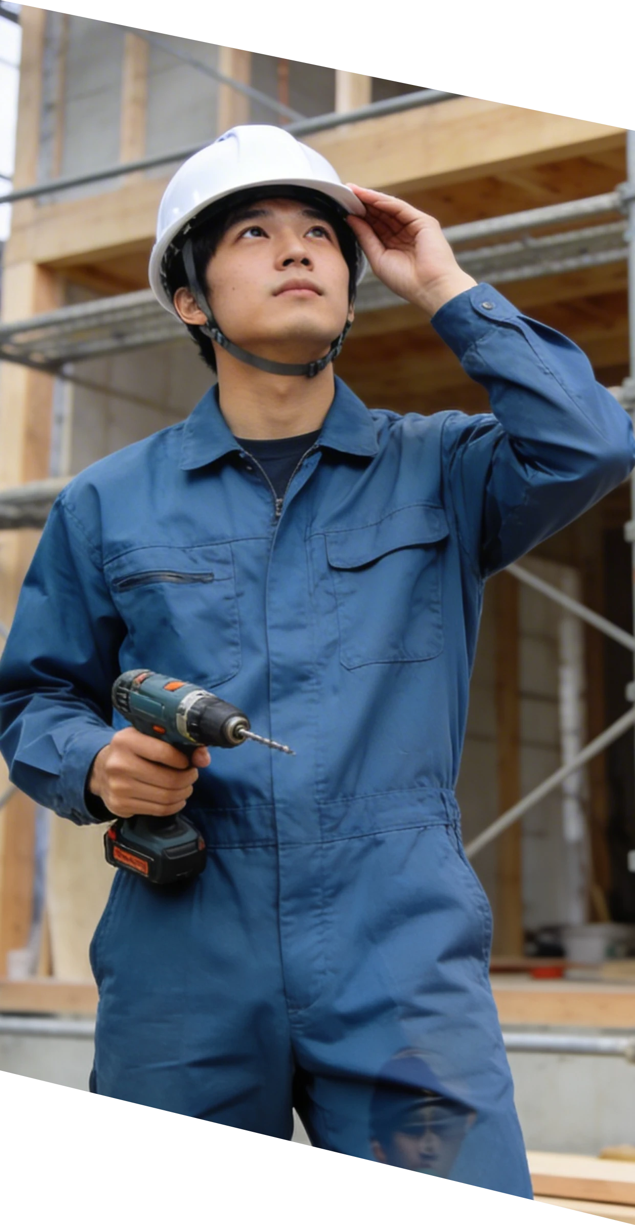 工具を持って見上げる作業服姿の男性